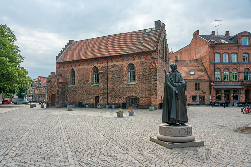 Lund, Sweden - June 9, 2022:  During the medieval time, the south vestry in the Lund Cathedral was used as library, which was possible while it only contained of a few volumes, due to the costly parchment on which the hand-made scripts were written. Henric Schartaus is the man in the statue, he was a priest from 1785 until his death, 1825.