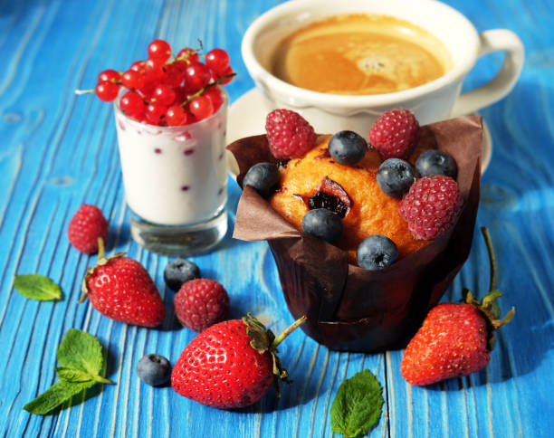 Cupcake with berries, a cup of coffee and yogurt with red currants. Close up.