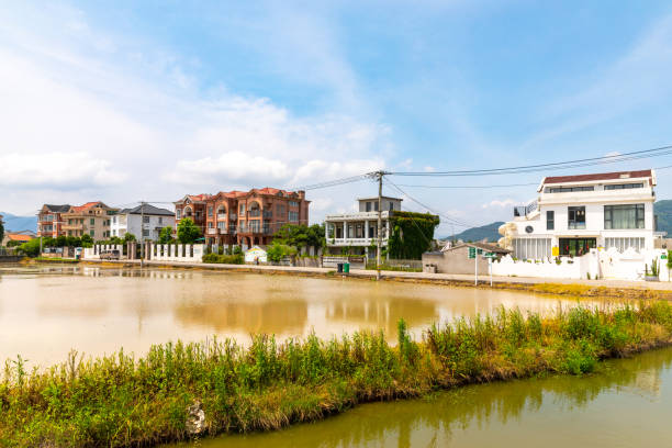 Wenzhou, Zhejiang Province, China - July 19, 2022:  A group of buildings with diverse architectural styles. Across the road there is water. Real life in the suburbs of the city. No people are seen in the scene.