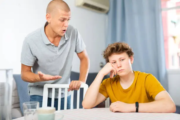 Dissatisfied father scolds young son at home