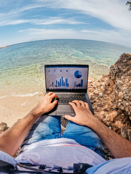 istock Young Man Working On Laptop At The Beach 1406041926