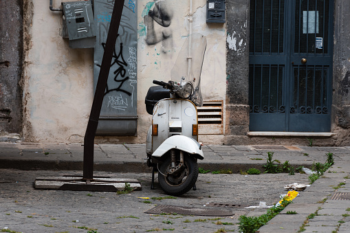 Naples, Italy. May 27, 2022. Old white Vespa scooter parked on the side street of Naples, Italy