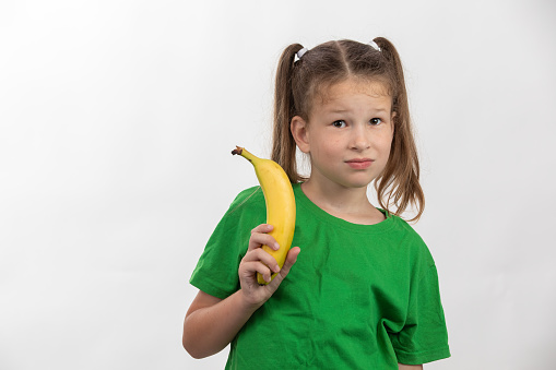 Funny portrait of cute little girl with banana on white background