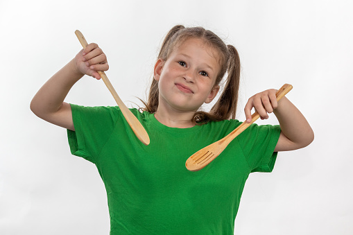 A young girl shows that she loves to cook with her wooden cooking spoons