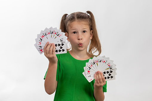 Close up portrait of caucasian girl with playing cards. Isolated on white background. Childhood concept.  Free time, fun, hobby, girl magician.