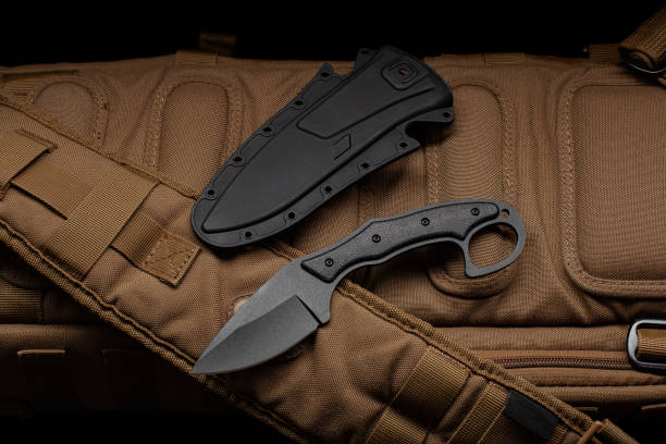 istock A small knife with a plastic sheath on a sand-colored military backpack. Dark background. 1406047471