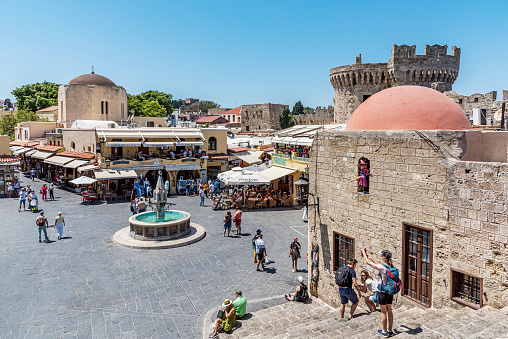 Rhodes Island, Greece - May 23, 2022: Tourists on the historic Hippocrates Square, in the Old Town center of the island of Rhodes, Greece. Hippocrates Fountain.