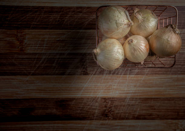 A basket of onion's on a cutting board ready for prep.