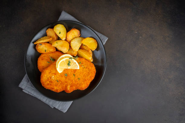 Chicken schnitzel with sauce, fried potatoes and lemon in a plate Chicken schnitzel with sauce, fried potatoes and lemon in a plate schnitzel stock pictures, royalty-free photos & images