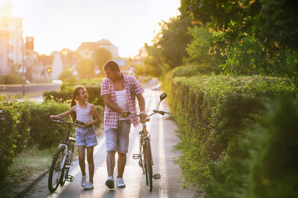 istock Father and daughter pushing bikes on a bicycle lane and having fun 1406053853