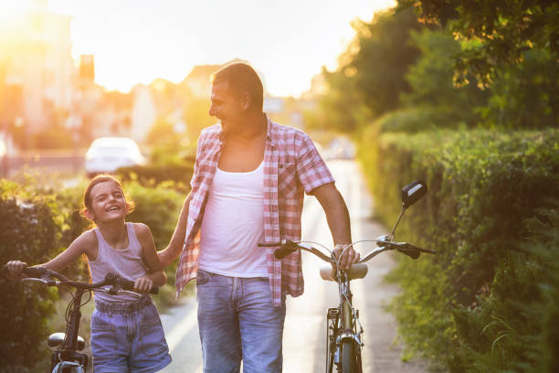 istock Father and daughter pushing bikes on a bicycle lane and having fun 1406054095