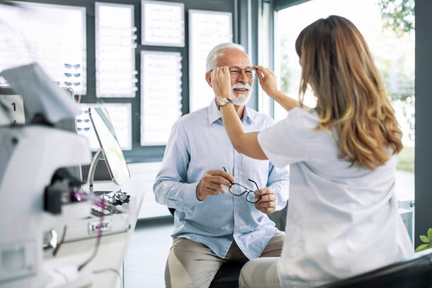 istock Senior examining eyes trying on glasses 1406056541