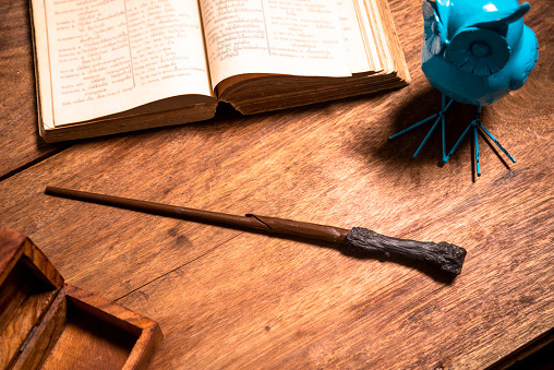 magic wand on a wooden table with an open book.