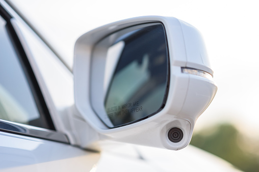 Rear view mirror cover with surround view 360 degrees camera. A camera system on right side mirror on car to help drivers can see a blind spot area. Parking assistance technology and car help systems.