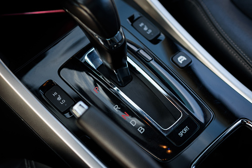 Gear shift stick into P position, (parking) symbol in automatic transmission car. Modern automatic gearbox hybrid car. Close up of the gear box transmission handle. Car detailing. Interior car inside.