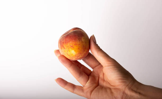 istock woman holding a peach 1406060151
