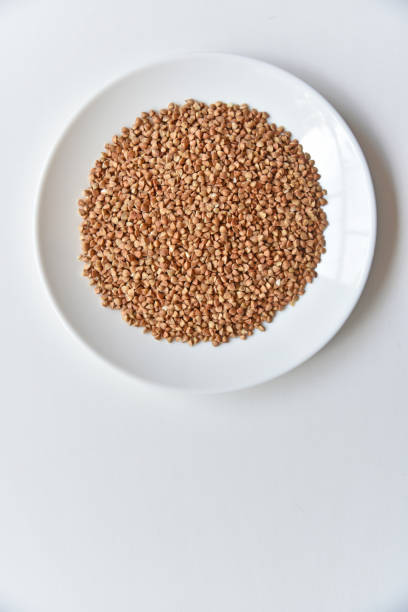 Buckwheat grains in a white plate close-up. Rustic buckwheat grains white plate. Healthy eating.