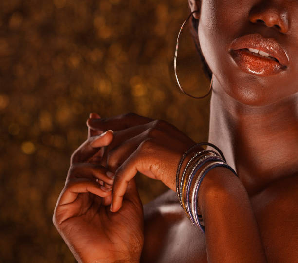 Beautiful young African woman with bright make up posing against a gold background.