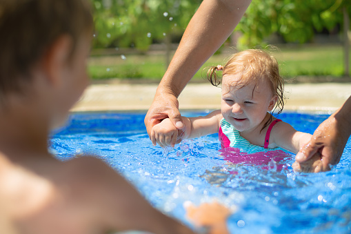 Happy laughing toddler girl having fun in a swimming pool