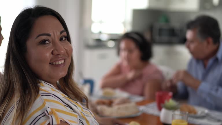 Portrait of mid adult woman eating breakfast with her family at home