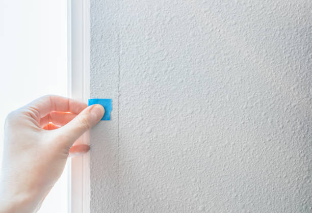 Hand put a blue sticker on defect construction. A person's hand sticks a blue sticker on paint cracked wall, checking the quality of house defect construction. Interior inspection of the mark, material and surface for fix and repair. Home Improvement concept. painted drywall texture stock pictures, royalty-free photos & images