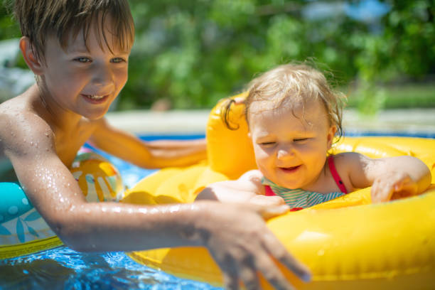 istock Little boy playing with his baby sister in inflatable ring 1406079077