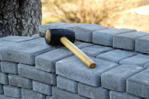 istock Defocus paving hammer. Stack of paving stones. Garden brick pathway paving by professional paver worker. Laying gray concrete paving slabs in house courtyard on sand foundation base. Out of focus 1406079106