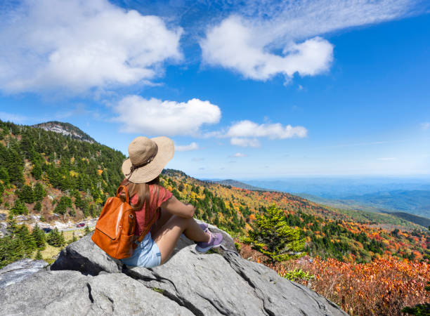 istock Hiker girl sitting on a cliff edge enjoying scenic fall view. 1406081575
