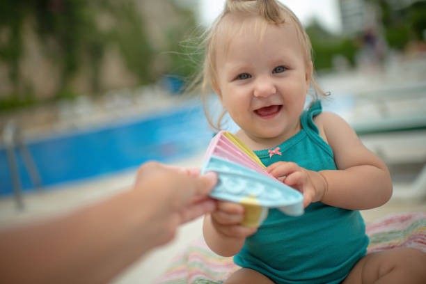 Mother giving her baby girl pop it toy