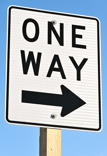 Closeup of ONE WAY sign on clear day.