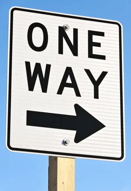 Closeup of ONE WAY sign on clear day.
