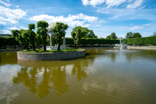 Idyllic view on Pond in Kadriorg   and fountain  inside pond and small island with trees and white alcove