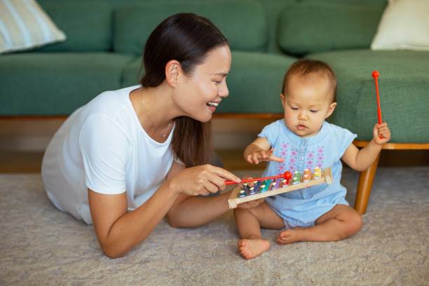 A mother playing toys and teaching her baby at home. Children learning and development. stock photo
