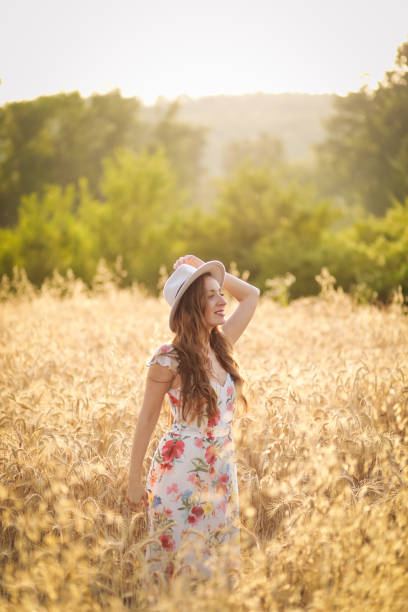 happy young woman in wheat field by sunset