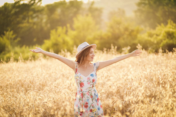 istock happy young woman in wheat field by sunset 1406093071