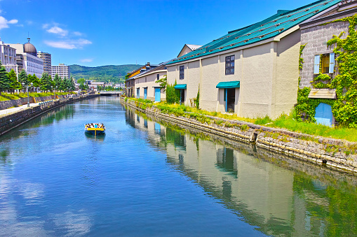 Fresh green Hokkaido Otaru city, clear Otaru canal warehouses and canal cruise ships seen from Asakusa Bridge Town Park