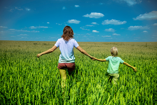 Mid adult woman and boy enjoyng freedom in the wheat field on a summer day