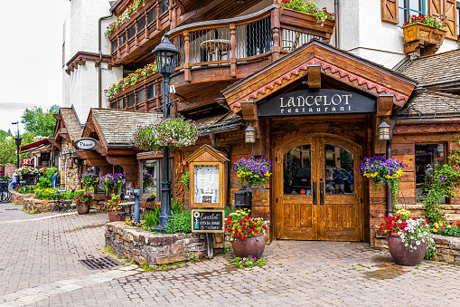 Vail, USA - June 29, 2019: Swiss style resort town in rocky mountains of Colorado with Lancelot restaurant sign entrance by shops on Gore Creek drive
