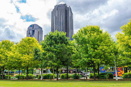 Dallas, USA - June 7, 2019: Downtown Klyde Warren park in summer with lawn grass, trees, food trucks and buildings towers cityscape on cloudy day in Dallas, Texas