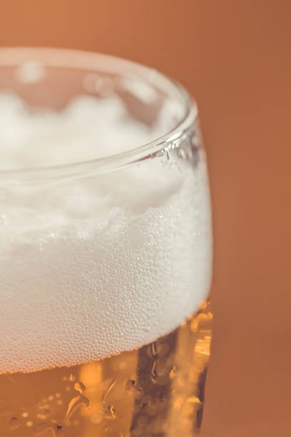 ビールグラスの白い泡。ガラスのゴブレットに入った新鮮なビール。ビールの泡のクローズアップ。ビールのクローズアップ - gasoline brewery beer liquid ストックフォトと画像