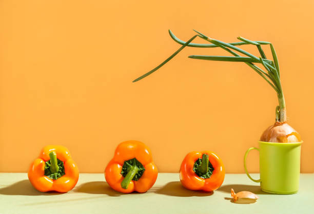 cebola em um copo. pimenta amarela fresca e cebola verde sobre a mesa. pimentões e cebolas verdes jovens na mesa de jantar - pepper bell pepper market spice - fotografias e filmes do acervo