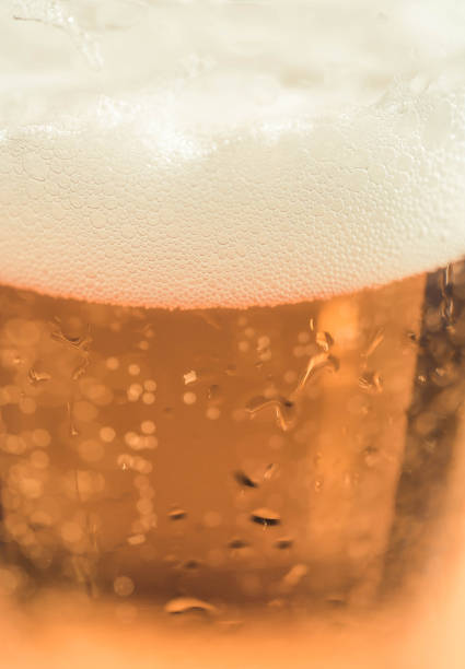 ビールグラスの白い泡。ガラスのゴブレットに入った新鮮なビール。ビールの泡のクローズアップ。ビールのクローズアップ - gasoline brewery beer liquid ストックフォトと画像