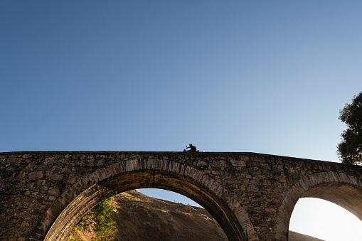 Biker crossing a large stone bridge