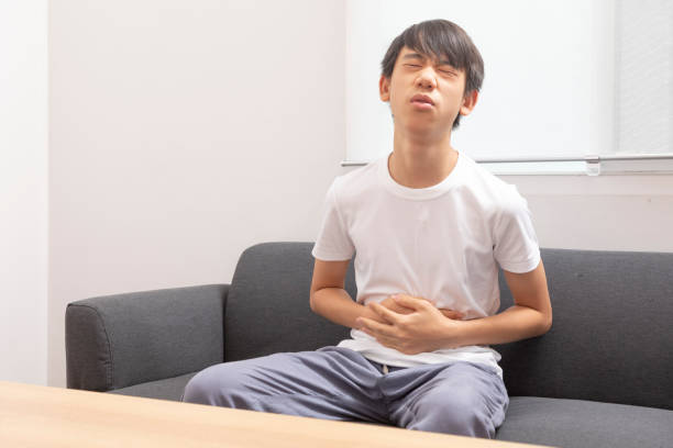 азиатский мальчик-подросток страдает от боли в животе - teen obesity стоковые фото и изображения