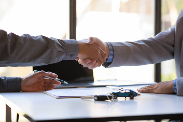 las ventas de servicios de alquiler de coches dan el concepto clave del coche. vista de cerca mano del agente apretón de manos al cliente después de firmar el formulario de contrato de alquiler. - car insurance sales occupation buying fotografías e imágenes de stock