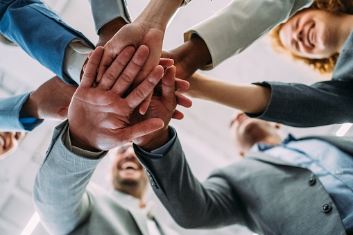 Shot of multi-ethnic group of business people with stacked hands showing unity and teamwork. Low angle view of successful business people stacking hands in the office.