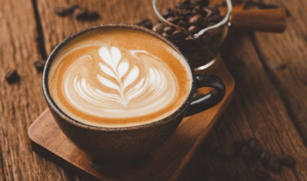 latte art na gorącej kawie latte. aromatyczna filiżanka kawy i ziarna kawy na drewnianym biurku. - froth art zdjęcia i obrazy z banku zdjęć