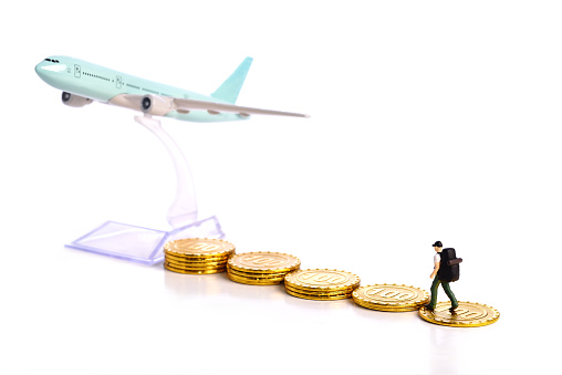 Travel Concept. Miniature travelle figure walking on pile of money coin to airplane