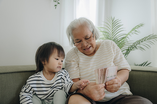 Grandmother holding money and embracing granddaughter at home