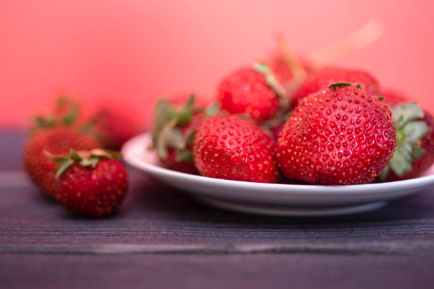 Fresh strawberries in a white plate on a dark wooden background. The concept of fresh and healthy food. copy space.
